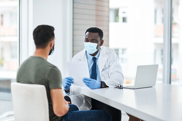 Fototapeta na wymiar Where theres a doctor, theres a cure. Shot of a masked doctor having a consultation with a man.