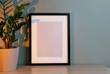 Fototapeta na wymiar Blank frame mockup for artwork or print on green wall background.