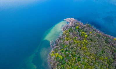 Naklejka na ściany i meble Top down view of the island in the lake. Blue water and mixed trees.