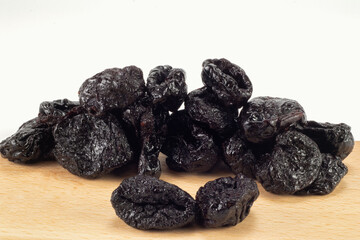Dried plums on wooden plate and bright background. Close up view.