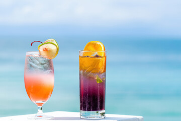 Cocktails in luxury exotic resort in summer sunny day. Travel, vacations, holidays, tourism concept. Turquoise sea blurred background. Fruit mocktail iced drinks in tropical luxurious hotel. Close-up.