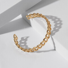 Chain shape golden cuff bracelet on geometric white background with copy space - obrazy, fototapety, plakaty