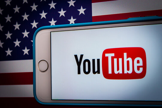 Kumamoto, JAPAN - Feb 22 2022 : The conceptual image of Youtube logo on an iPhone on an American flag background in a dark mood