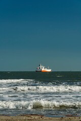 Cargo ship on the horizon of Santos bay, Brazil on a blue sky day.