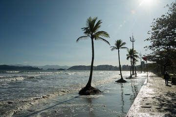 High tide invades the strip of sand to the sidewalk by the sea. City of Santos, Brazil. 