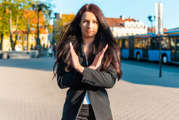 Obraz premium Pretty business woman with her arms crossed at her chest demonstrates break the bias symbol of woman's international day.Woman show solidarity,breaking stereotypes, inequality.sunset city outdoors.