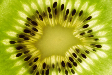 Close-up of a piece of fresh ripe kiwi green. Kiwi or Chinese gooseberry close-up. Fresh juicy slice of fruit with seeds. Wallpaper with kiwi fruit texture