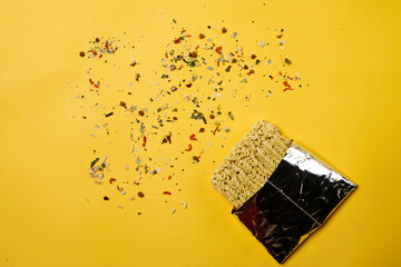 Instant noodles composition. Noodles and fresh vegetables and spices on yellow background