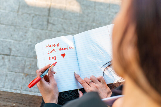 Woman writes in a notebook, holds felt-tip pen in her left hand.Outdoors summer evening park. Left-handers Day August 13th.Closeup. - Powered by Adobe