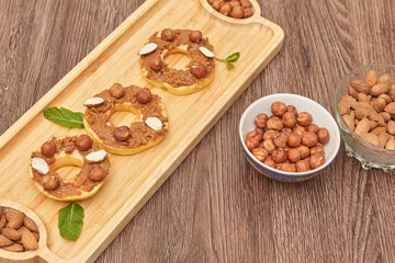 Apple rounds dialed on top of each other with peanut butter, almonds and nuts, on wood plate on the table. Healthy food