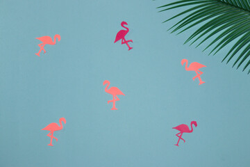 pink flamingos on a pastel blue background, in the corner of a palm leaf, creative summer design