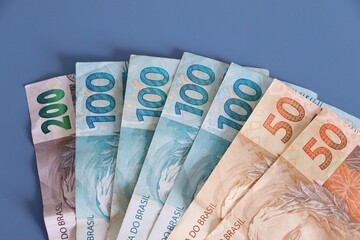 Brazilian Real banknotes on blue background. Brazilian money. Finance concept. 
