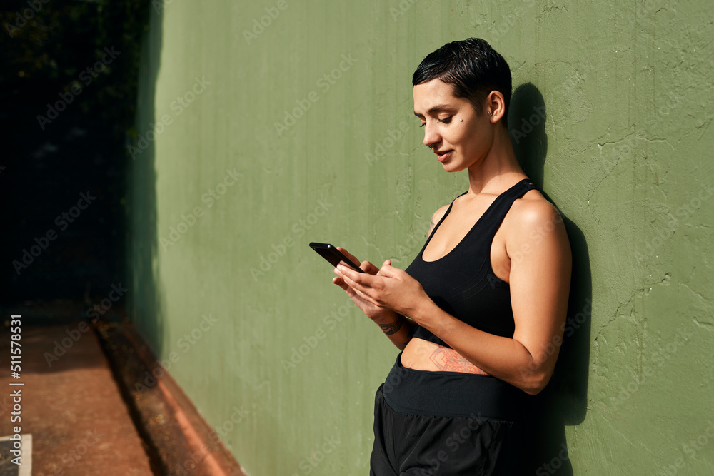 Sticker Going through my social media. Cropped shot of an attractive young sportswoman standing alone and using her cellphone after a basketball game.