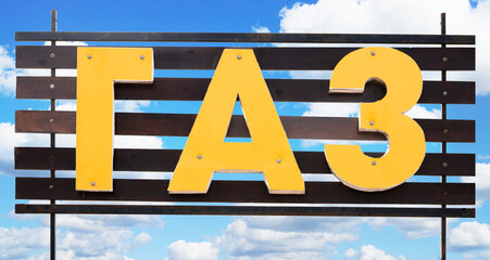 Sign with the word gas written in Russian on the blue cloudy sky background