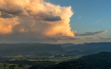 Cumulus clouds at sunset with the view over the valley and mountains.
