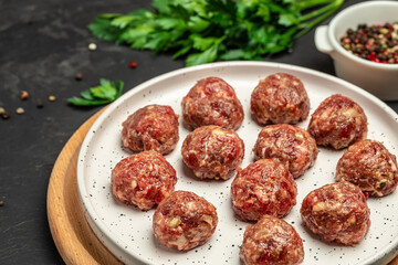 Raw meatballs, minced pork meat on white plate dark background. Culinary, cooking concept. Food recipe background. Close up