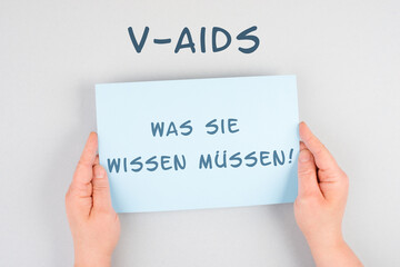 The words v-aids, what you need to know are standing in german language on a paper, new autoimmune...