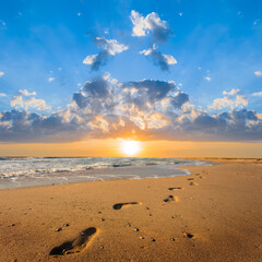 Fototapeta na wymiar sandy sea beach with human track on sand at the sunset, natural summer sea vacation scene