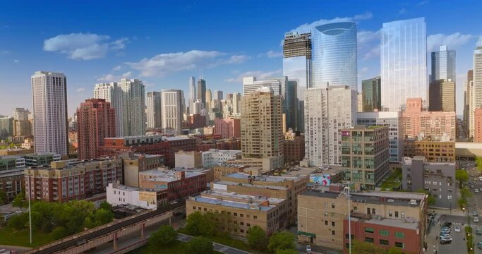 Chicago buildings in the bright light of sun. Drone footage rising up. Blue sky with clouds at backdrop.