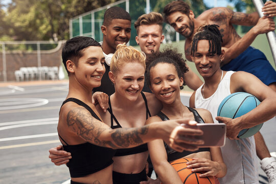 Lets take one of the best team. Shot of a group of sporty young people taking selfies together on a sports court.