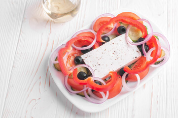 top view of greek salad closeup and jar with olive oil on white wooden background