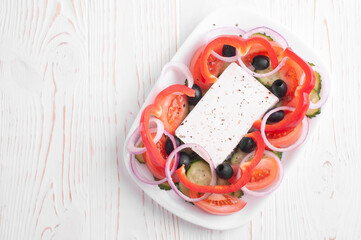 top view of greek salad on white wooden background