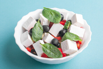 Greek salad in a white bowl on a blue background