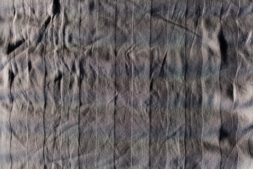 Natural abstract background of grey wrinkled sheet with vertical lines.