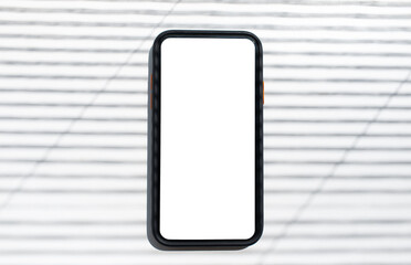 Close-up top view of smartphone with blank on screen, on striped background.