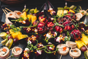 Luxury catering table, beautifully decorated banquet with variety of food snacks and appetizers on corporate birthday party event or wedding, delicatessen setting on black plate background