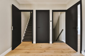 Closed black door of room located near framed pictures and stylish lamp on top of stairway at home