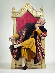 The thoughtful king. Studio shot of a richly garbed king sitting on a throne.