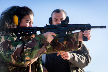 Trainer helping young woman to aim with handgun at combat training. High quality photo
