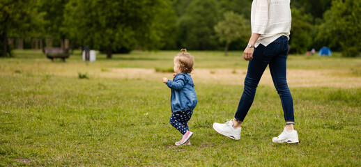 mother and daughter outdoors, having fun in park, toddler is running on the grass