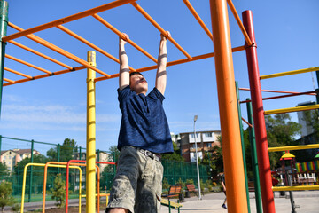 a teenage boy trains on a sports ground outdoors, he does physical exercises, a healthy lifestyle, a bright sunny day in summer