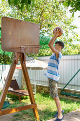 teenage boy playing basketball at home in the backyard, outdoor activities on summer vacation