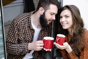 Young caucasian couple is traveling in travel van. Romantic atmosphere of relaxation. Road trip around country for the weekend. Man and woman sitting in camper and drinking tea. Millennial generation