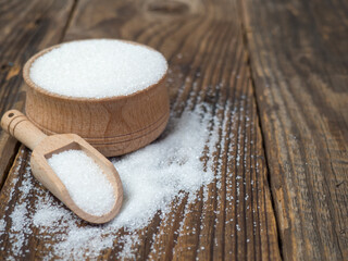 Stack of sugar cubes and granulated sugar in a wooden scoop