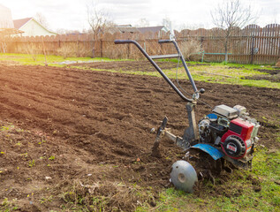 A man works the land in the garden with a cultivator, prepares the soil for sowing. farming concept