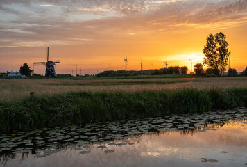 Obraz premium Dutch landscape with traditional windmill in Etten-leur and colorful sunset sky reflecting in the water