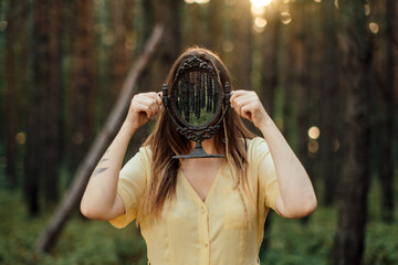 Woman with mirror instead of face on the forest background. Mindfulness, Mind and soul, Mental...