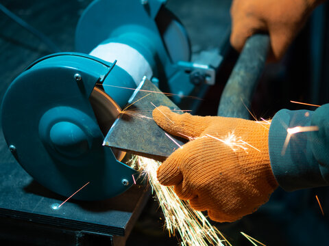 man sharpening an ax blade on a grinder