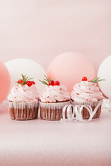 Three strawberry pink cupcakes on glitter background with air balloons, vertical card	with celebration concept