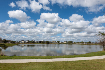 A curved sidewalk next to a lake that is a walking path in back of homes in Laureate Park Lake Nona...