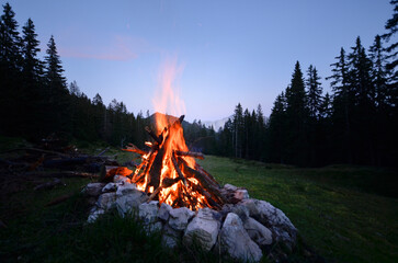 bonfire in the mountains, panoramic view, trees and forest silhouette background, - obrazy, fototapety, plakaty
