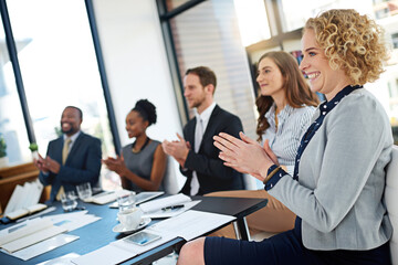 They seem truly impressed. Shot of a group of corporate businesspeople applauding while sitting in the boardroom.