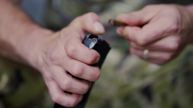 Close up shot of hands loading a magazine clip with bullets Man hands in camouflage clothes