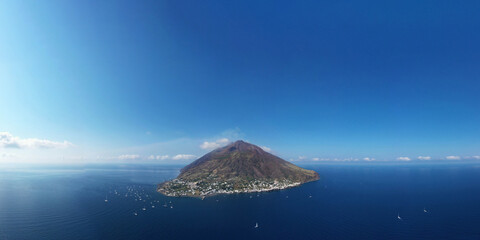Stromboli at Eolie island in a panoramic view from above with colorful sea and blu sky - aerial view