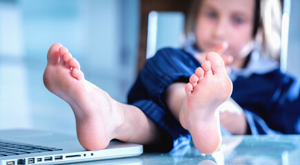 Young business girl with bare foots on the table in the office. Selective focus on foot.