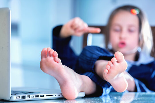 Funny portrait of young business girl with bare foots on the table in the office. Selective focus on foot. Horizontal image.